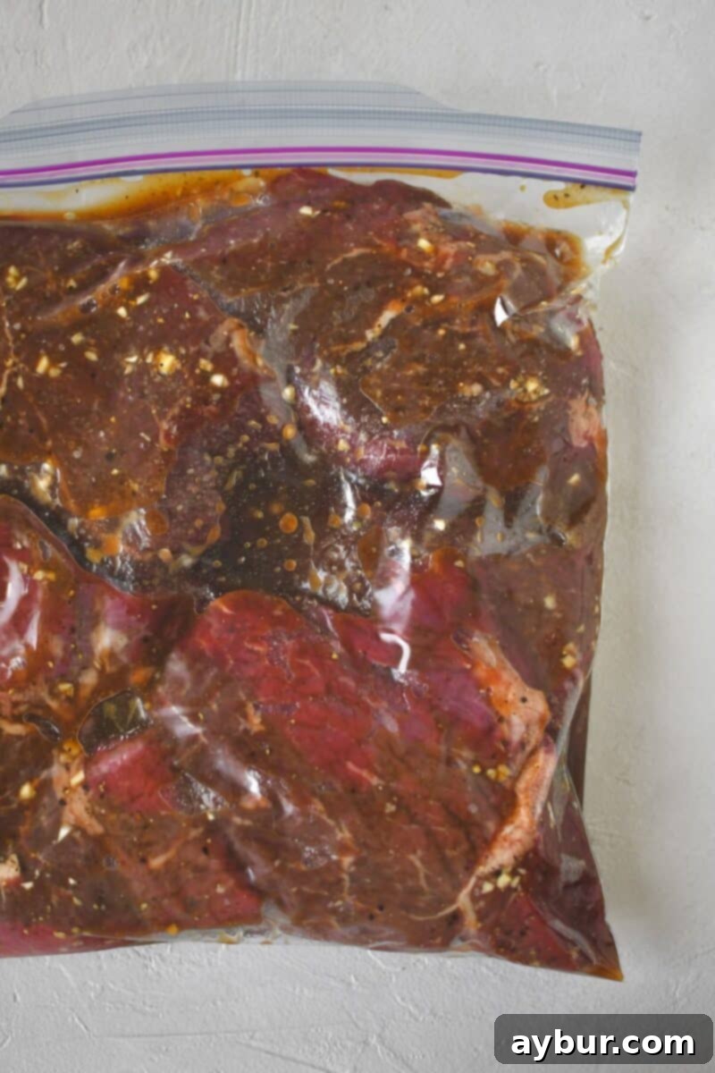 Steak and marinade mixed together in a zip-top bag ready to rest till cooked, showing the coated meat.