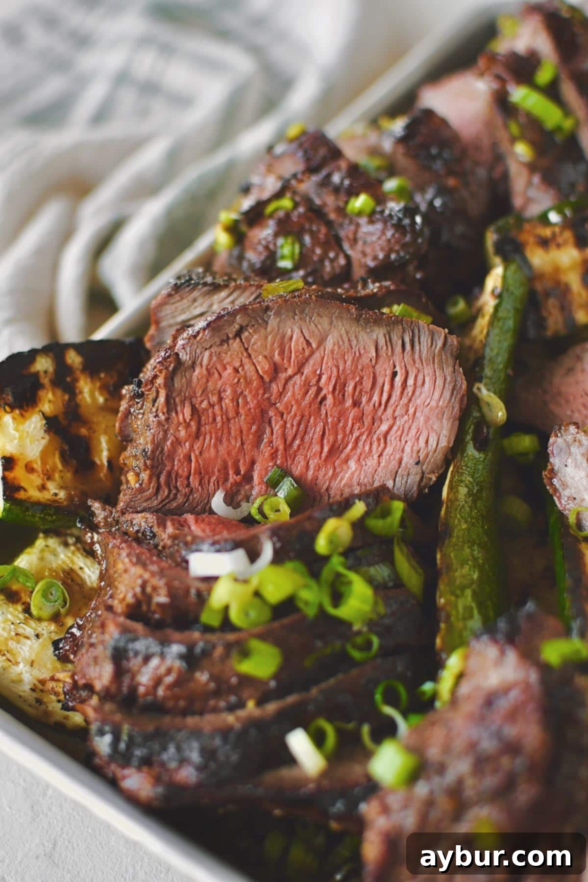 Best Marinade for Steak on the beef, after cooking and sliced and ready to be eaten, with a garnish of green onions.