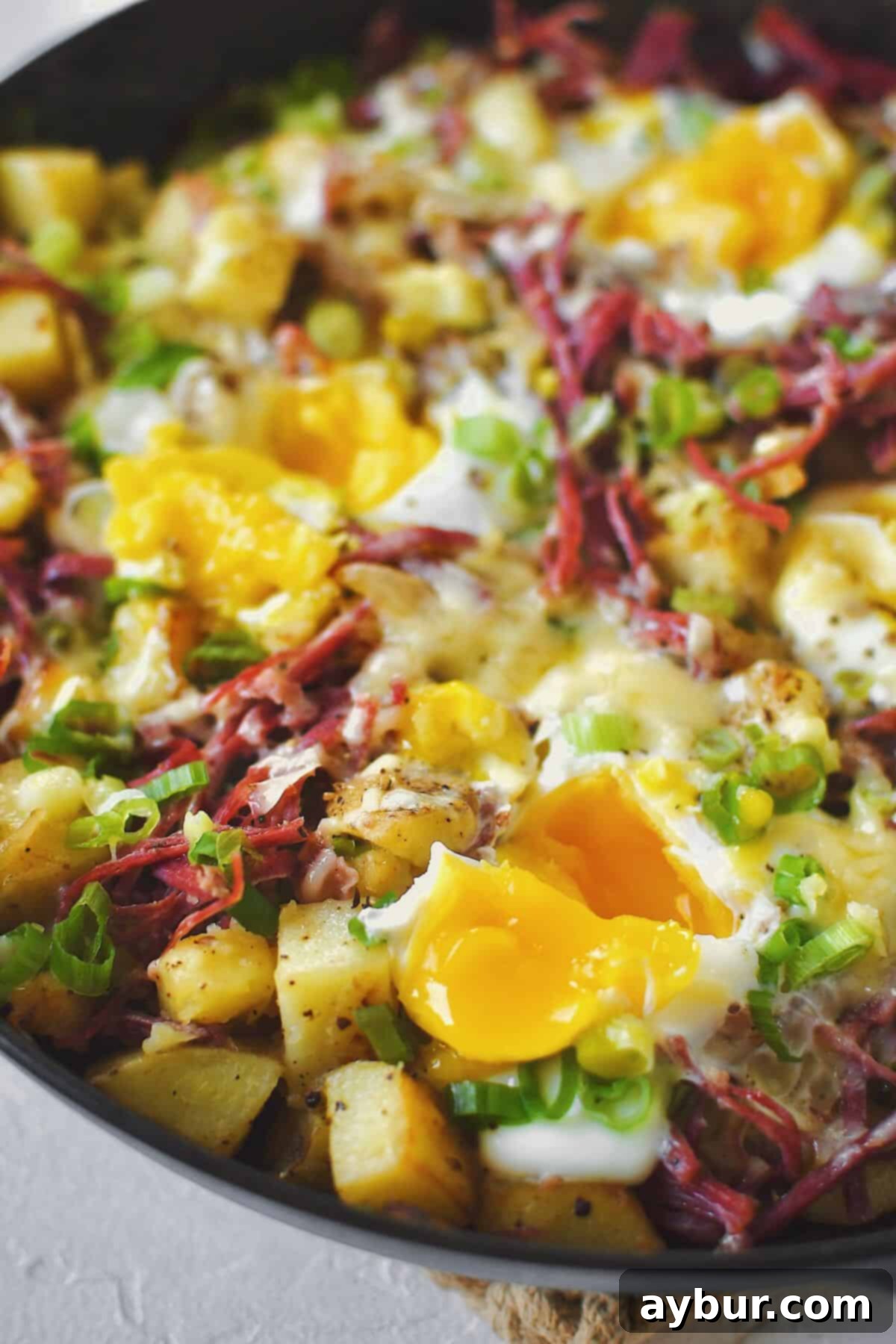 Perfectly cooked eggs nestled into a skillet of golden-brown corned beef hash, yolks ready to burst and enrich the dish.