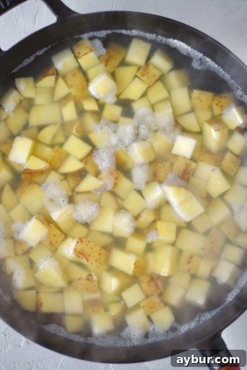 Diced Yukon Gold potatoes are par-boiled in a large skillet, softening them before they get crisped to perfection for the corned beef hash.