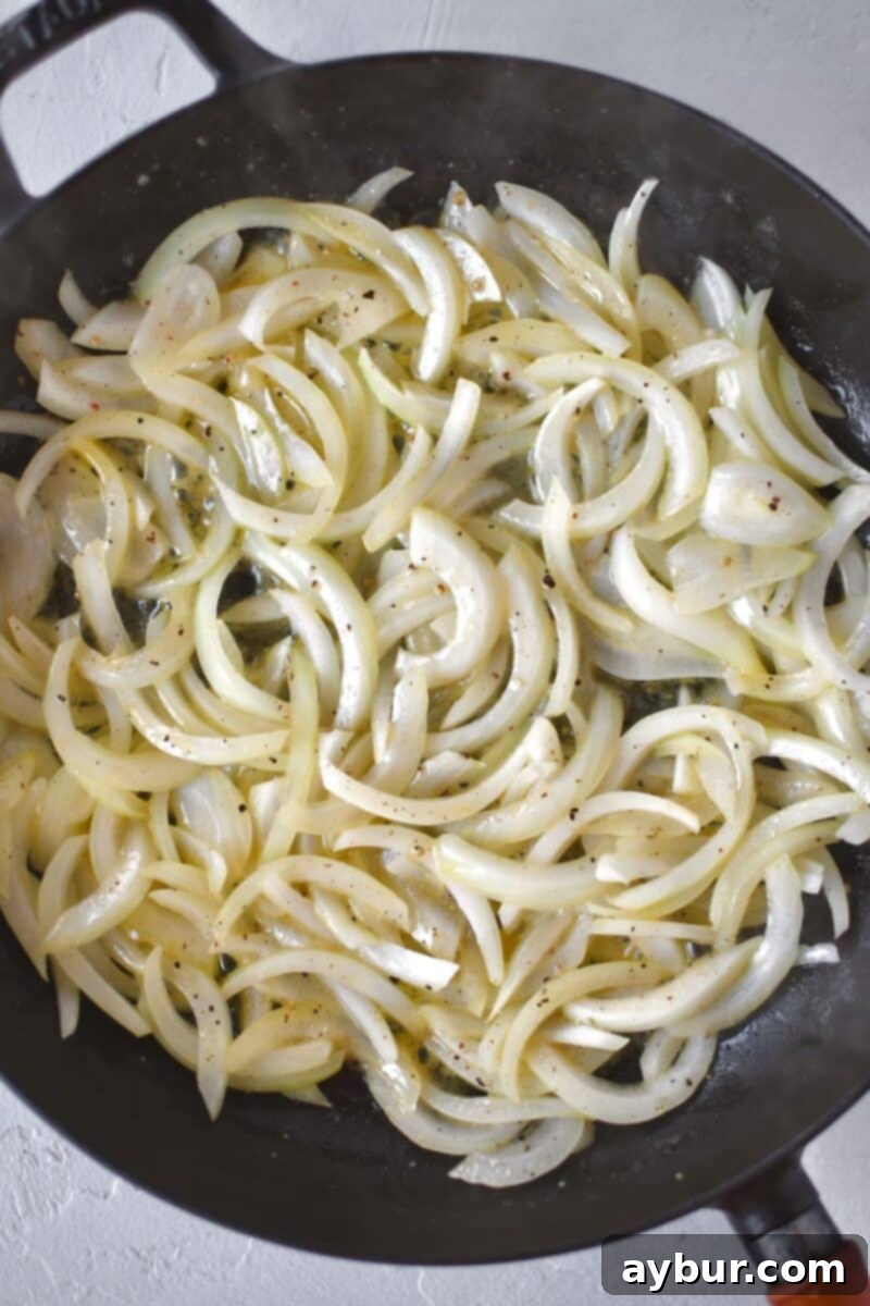 Sliced yellow onions are gently sautéed in rich Irish butter until soft and translucent, forming an aromatic base for the hash.