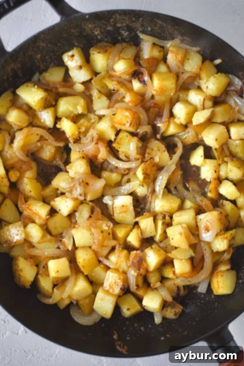 Par-cooked potatoes join the sautéed onions in the skillet, browning and crisping beautifully as they cook to develop a perfect texture for the corned beef hash.
