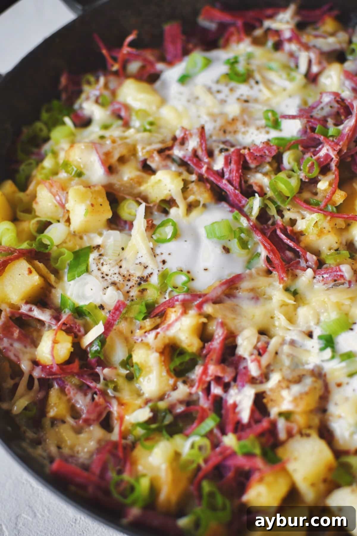 The finished corned beef hash, garnished with fresh green onions and melted cheese, showcasing perfectly cooked eggs with vibrant yolks, ready to be enjoyed.