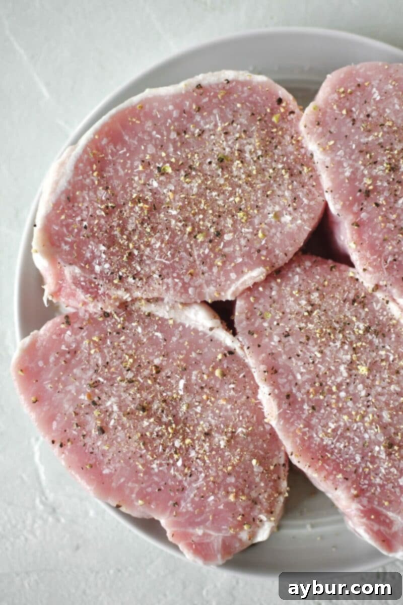 Perfectly Tender Sous Vide Pork Chops 4 Pork Chops seasoned on both sides with salt and pepper and resting on a plate.