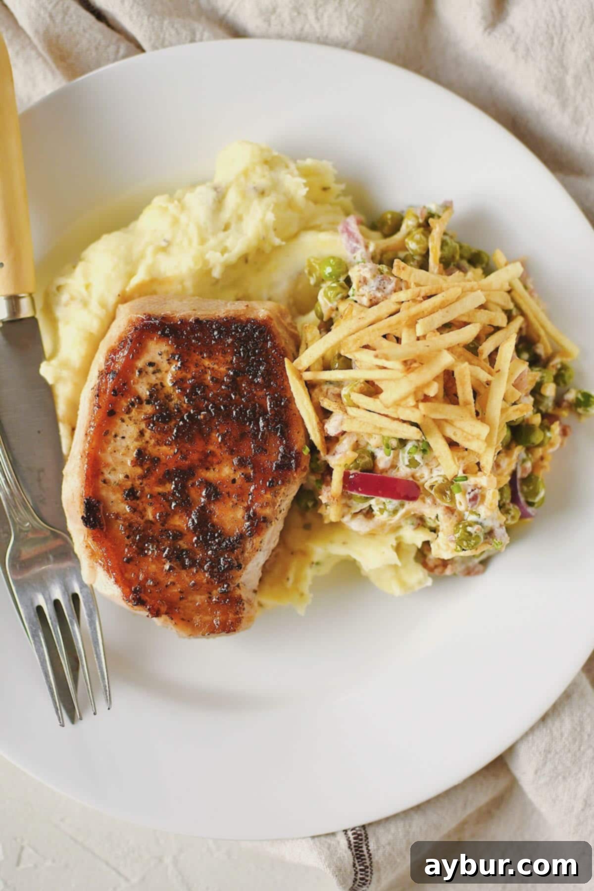 Perfectly Tender Sous Vide Pork Chops 10 Sous Vide Pork Chop served on a plate with mashed potatoes and pea salad.