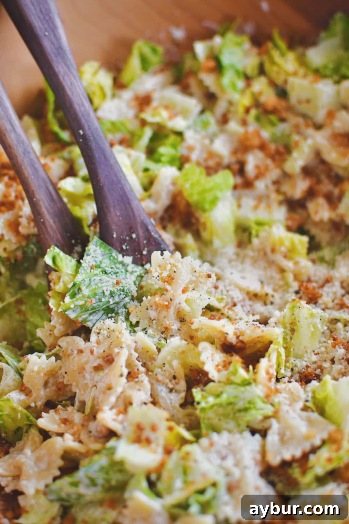 Savory Caesar Pasta Feast 2 Tossing the pasta, lettuce, and crumbs together in a large bowl, showcasing the vibrant ingredients of Caesar Pasta Salad.