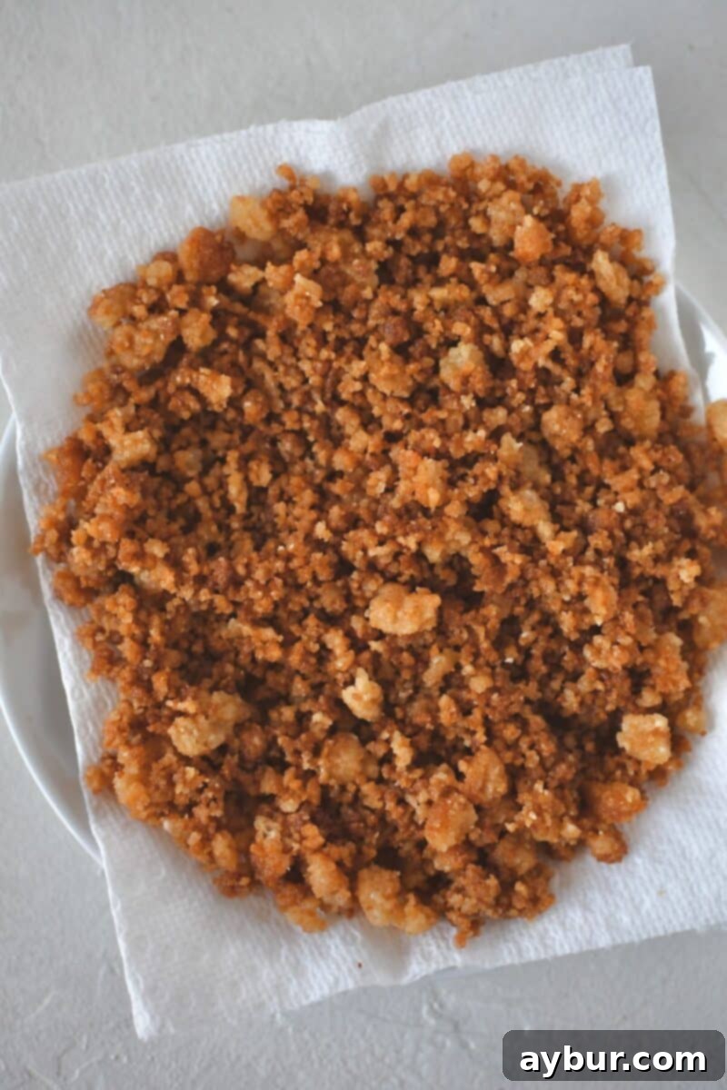 Golden brown and crisped parmesan bread crumbs resting on a paper towel-lined plate after being toasted, ready for the Caesar Pasta Salad.