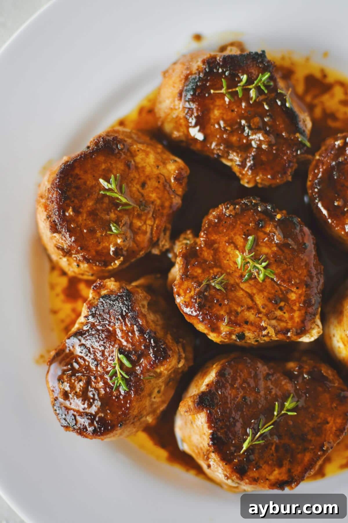 Perfectly cooked Pork Tenderloin Medallions basted with a rich pan sauce, presented on a plate, ready to be enjoyed.