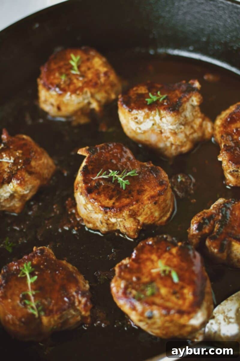 Returning the succulent Pork Tenderloin Medallions to the pan sauce for a final basting, ensuring every piece is coated.