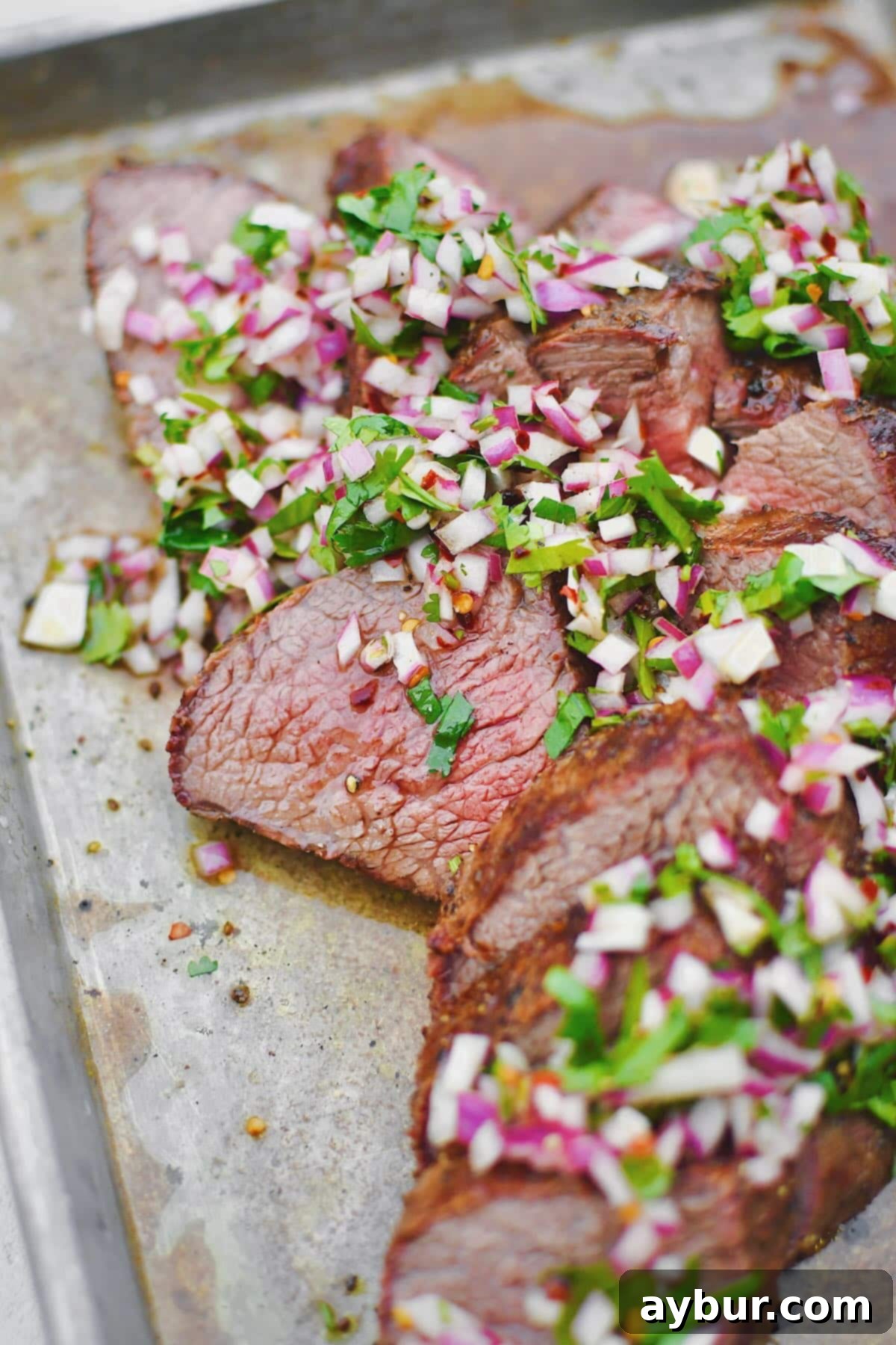 Perfect Tri-Tip Every Time 7 Tri-Tip, sliced against the grain, in two different directions, as is common with this cut of meat. Topped with an onion, cilantro, and vinegar relish.