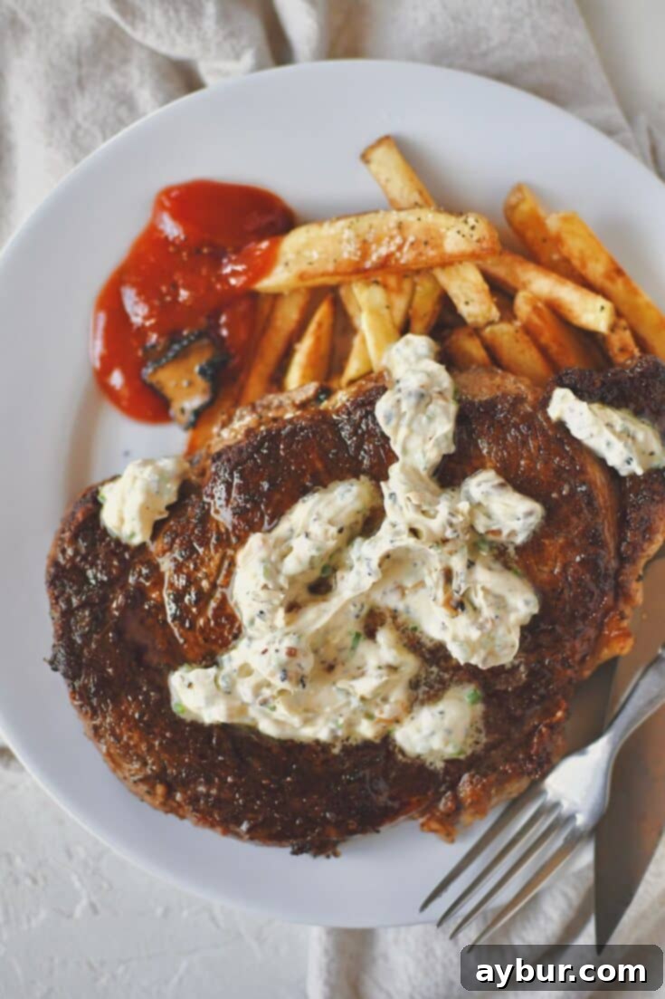 A beautifully plated Steak Frites dish, featuring a succulent ribeye steak generously topped with truffle butter and a side of perfectly golden, crispy frites, served with a rich truffle chili sauce.