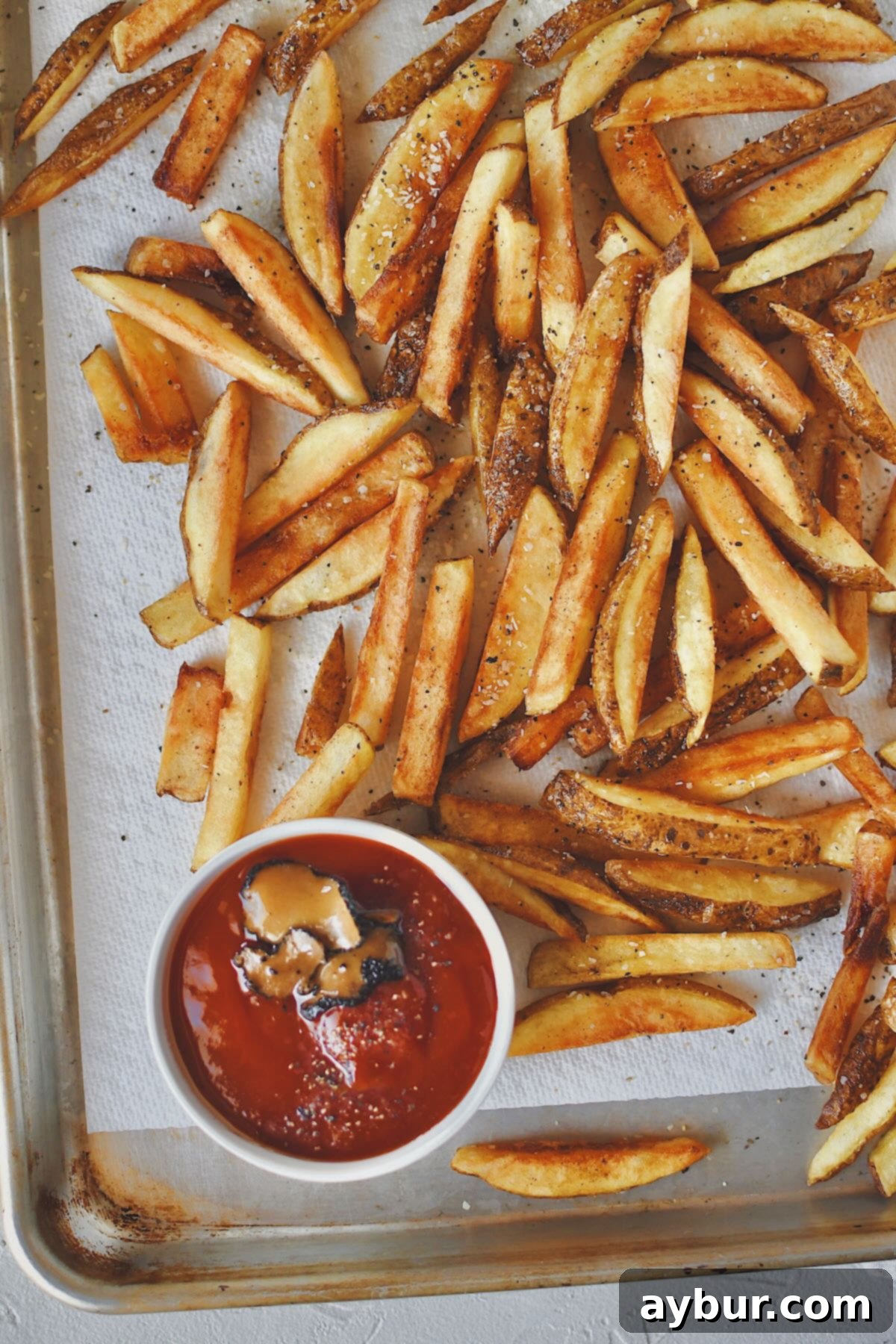 A close-up shot of perfectly golden-brown french fries, or frites, fresh out of the deep fryer after their second cook, highlighting their crisp texture.
