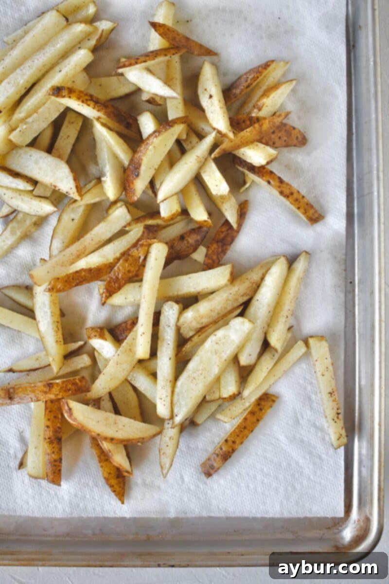 Partially cooked frites, light in color, after their initial 5-minute fry in 300-degree hot oil, ready for the second crisping stage.