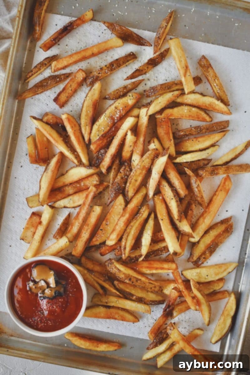 Golden-brown frites, fresh out of the deep fryer, cooked to perfect crispness and ready for immediate seasoning.