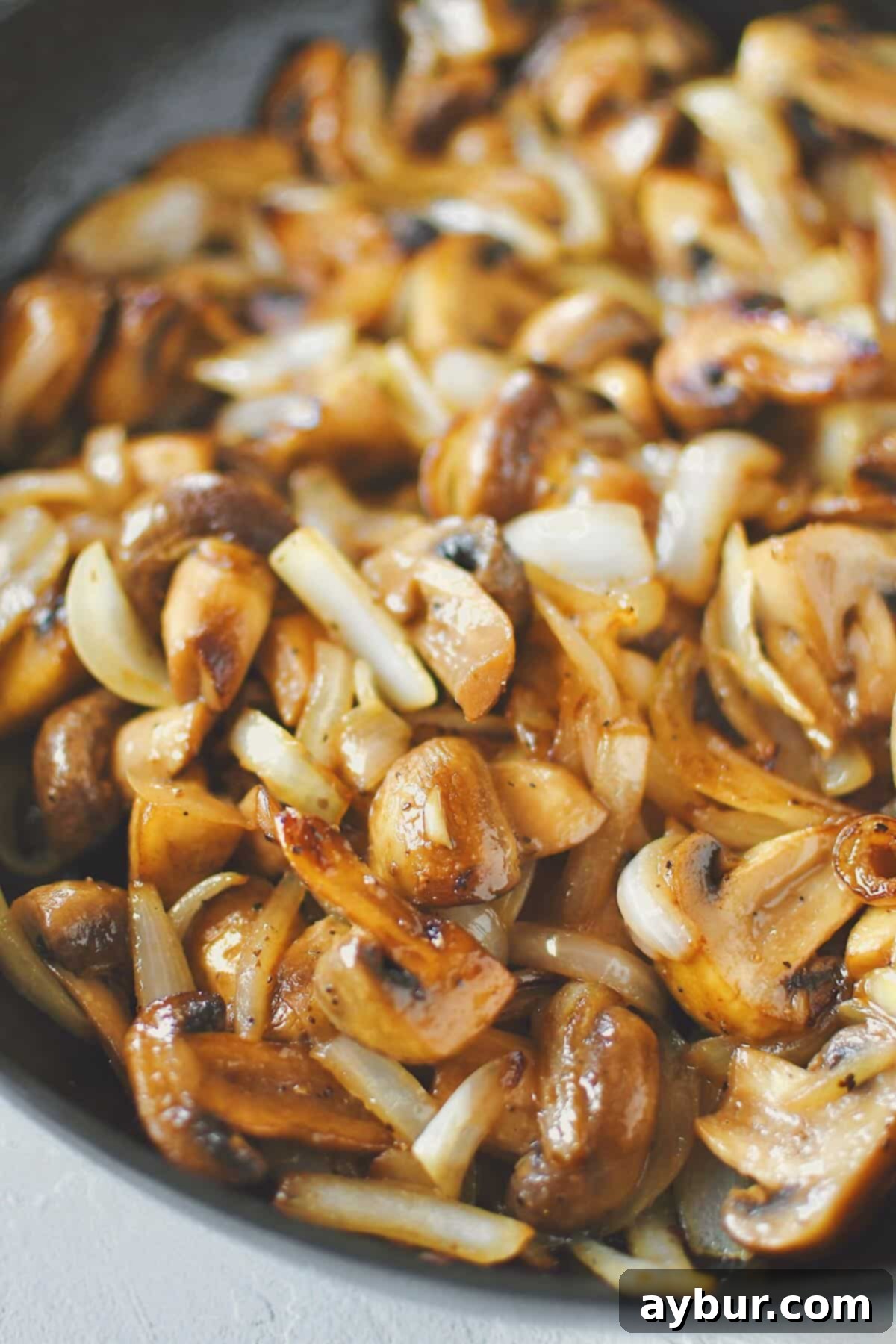 Caramelized Mushrooms and Onions 2 Perfectly Sautéed Mushrooms and Onions, golden brown and tender, served in a cast iron skillet, ready to be enjoyed.