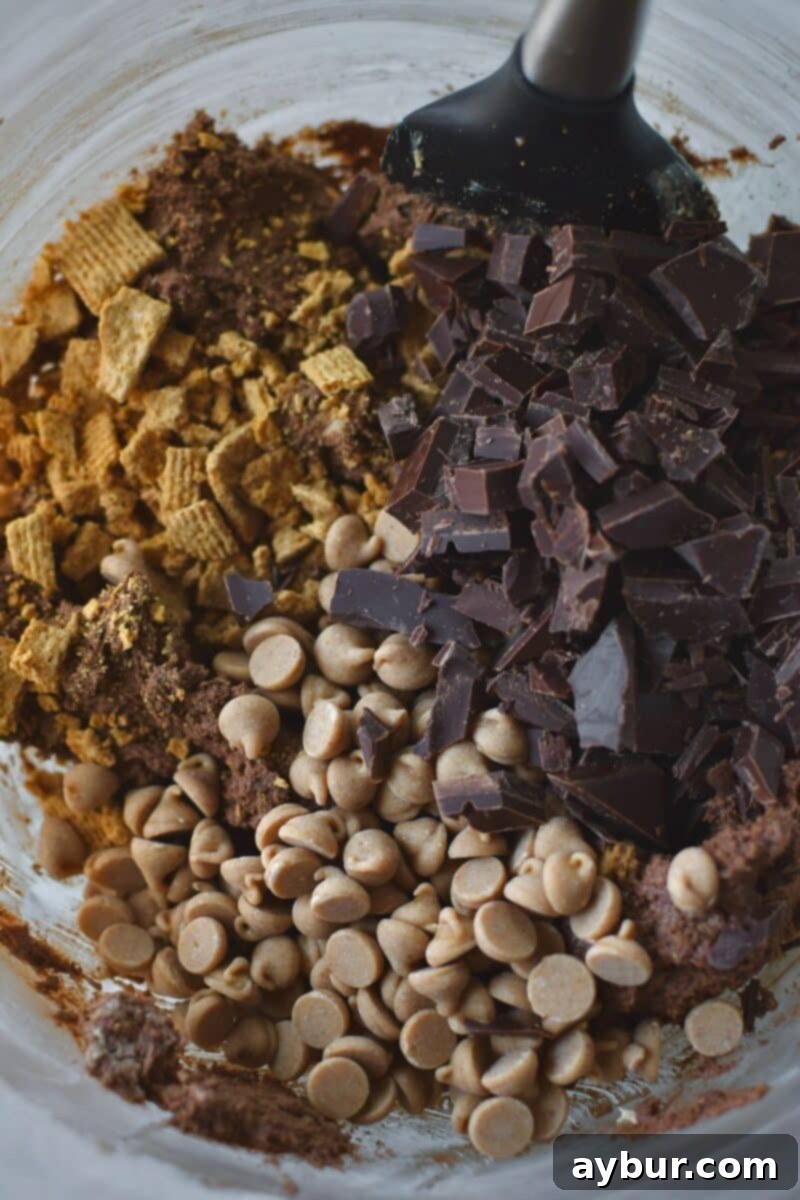 Gooey Chocolate Marshmallow Cookies 7 Adding chopped chocolate bar, peanut butter chips, and crushed graham cracker cereal to the cookie dough.