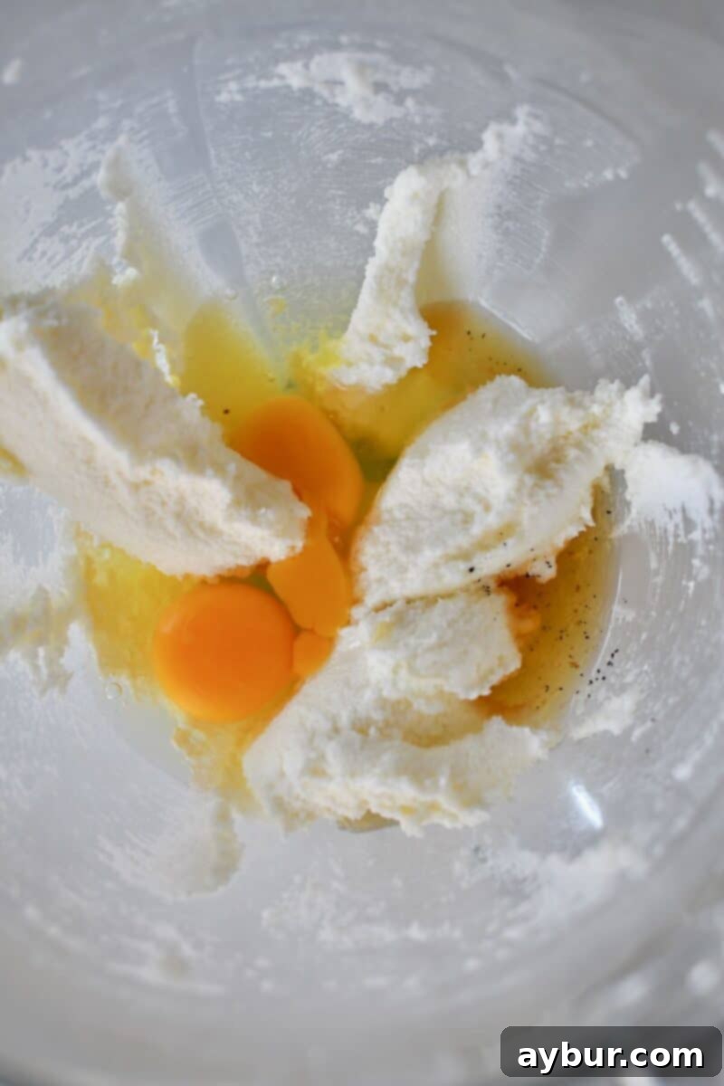 Adding the eggs and vanilla extract to the creamed butter and sugar mixture, ready for blending.