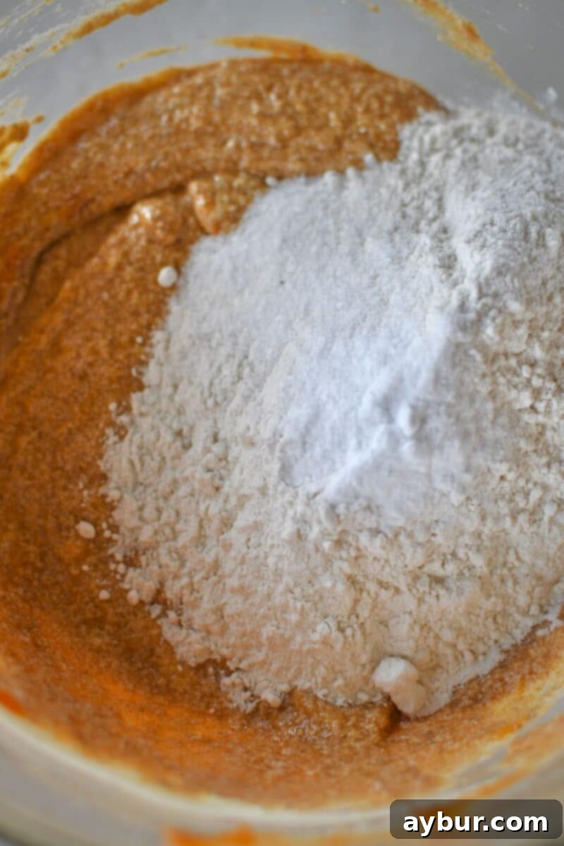Folding the dry ingredients into the wet batter, ensuring no streaks of flour remain for a tender crumb.