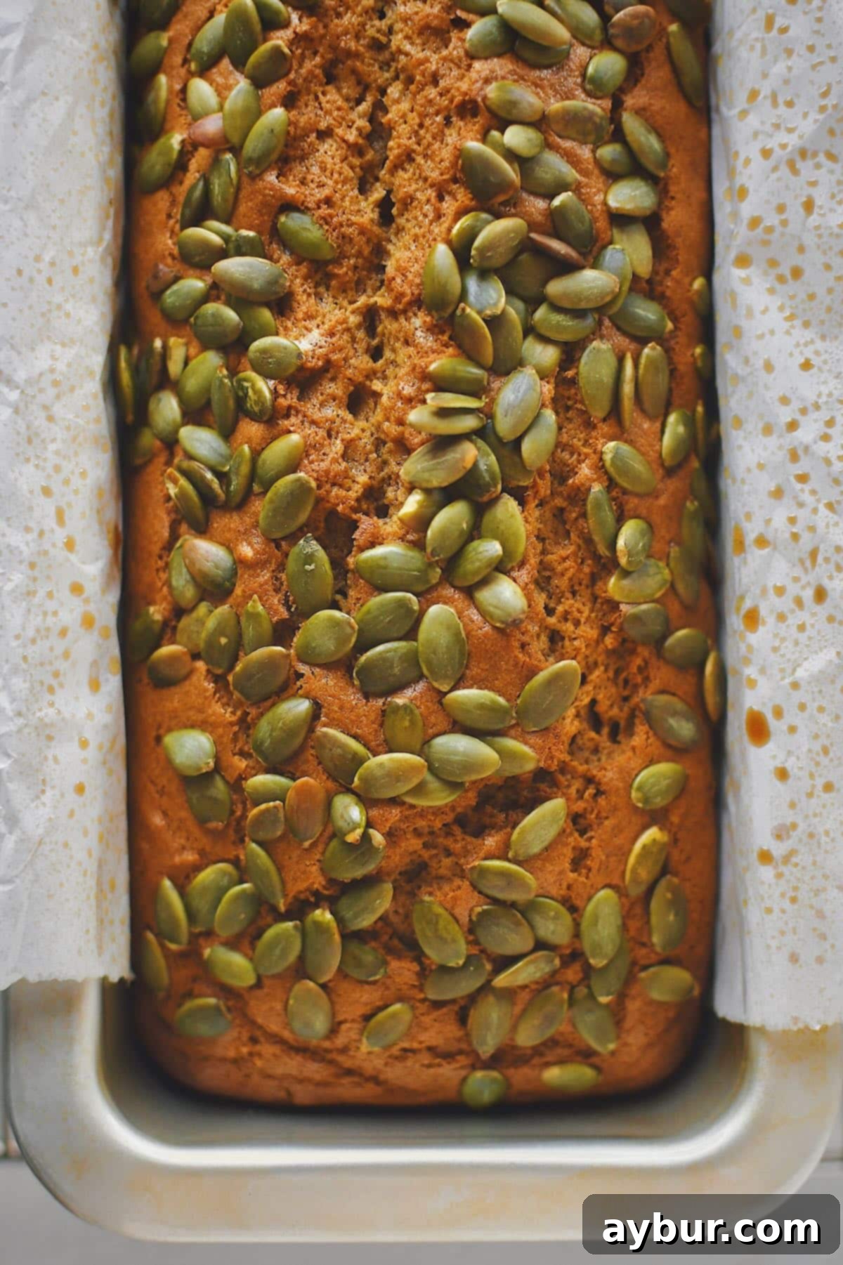 A freshly baked Pumpkin Spice Bread, golden brown with a perfect crack, cooling on a wire rack.