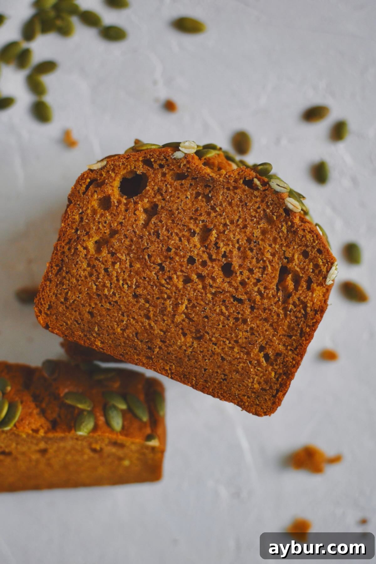 A single, perfectly sliced piece of Pumpkin Spice Bread, invitingly leaning against another slice.