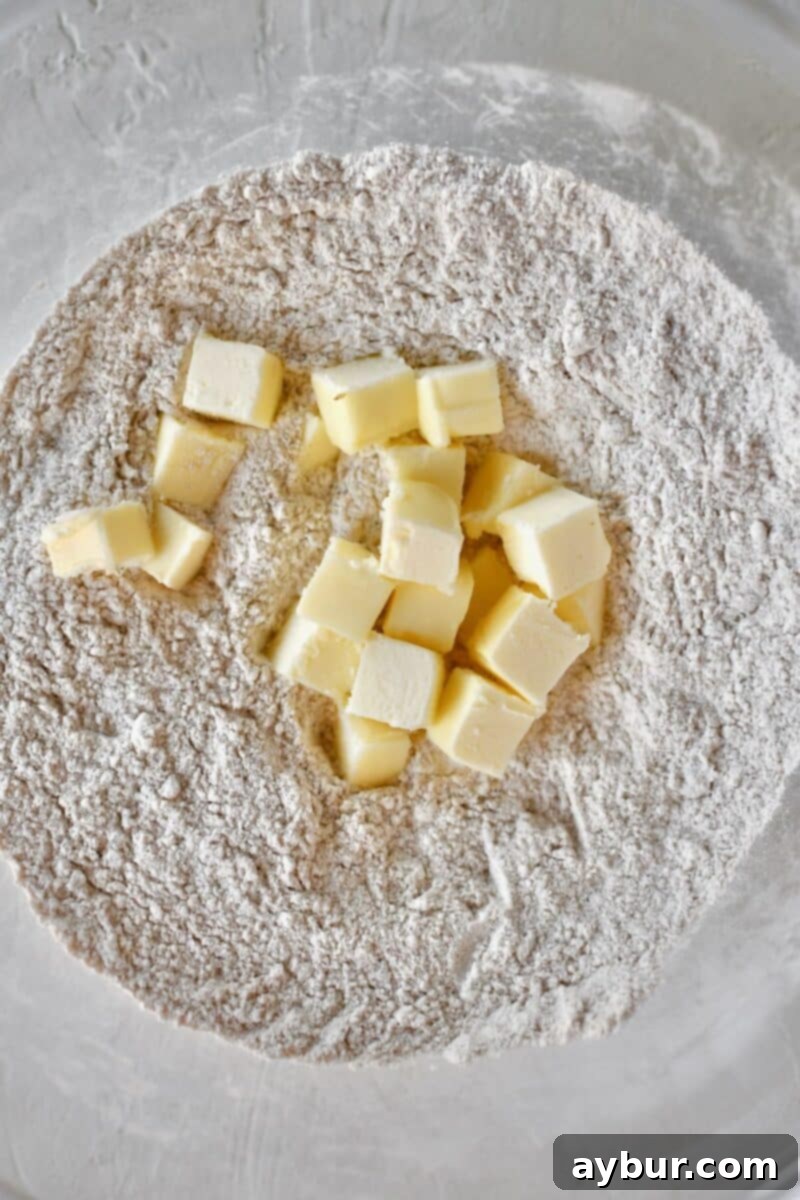 A wide shot of a large mixing bowl filled with the perfectly combined dry ingredients – flour, brown sugar, and pumpkin spice – just before the cold butter is cut in, showcasing the initial texture.