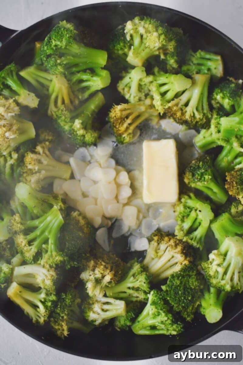 Adding the butter and sliced garlic to the pan with the white wine steamed broccoli.