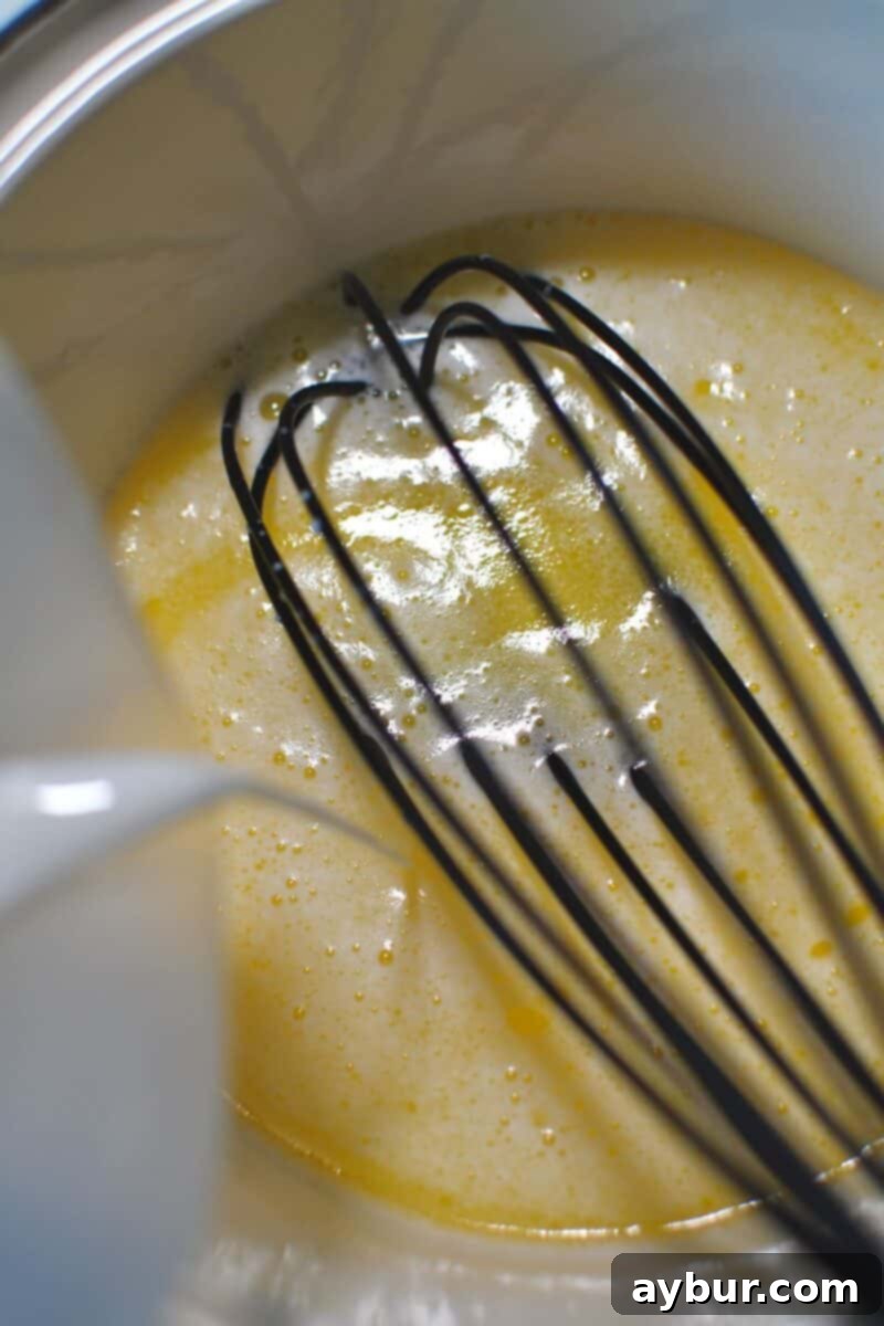 Buttermilk being poured into a saucepan with freshly melted butter, gently warming the mixture before adding it to the pumpkin puree.