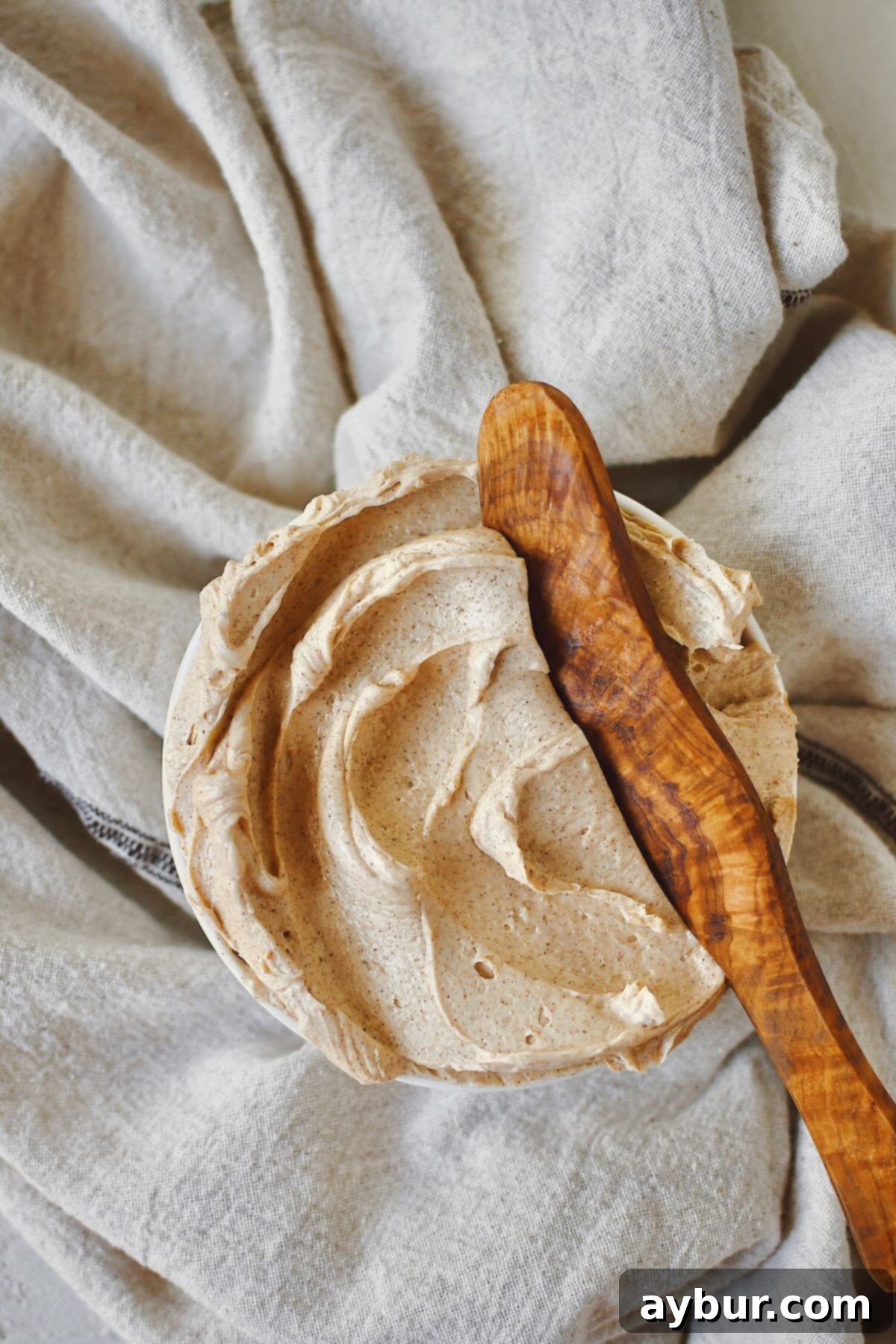 Sweet Cinnamon Butter 2 A shallow bowl filled with perfectly whipped Cinnamon Butter, with a wooden butter knife nestled in it, ready to be served on your favorite breakfast treats.