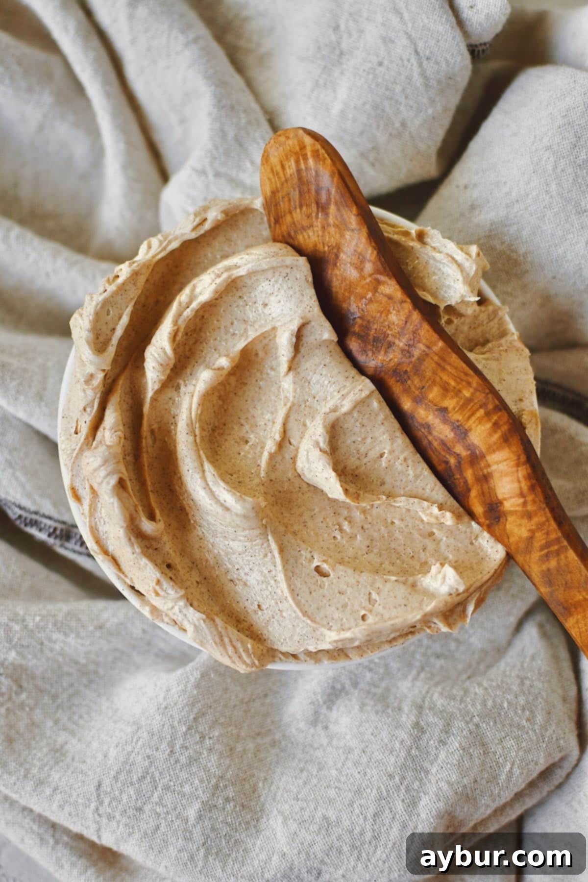 Sweet Cinnamon Butter 6 A close-up of a shallow bowl brimming with perfectly whipped Cinnamon Butter, ready to be spread. A wooden butter knife is invitingly placed, highlighting its creamy texture.