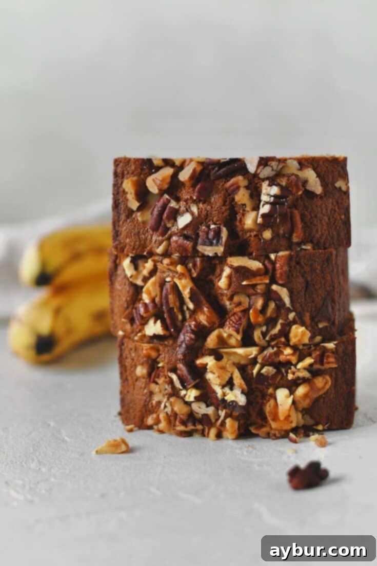 Sliced Starbucks Banana Bread Recipe stacked up with more bananas behind it, ready to eat.