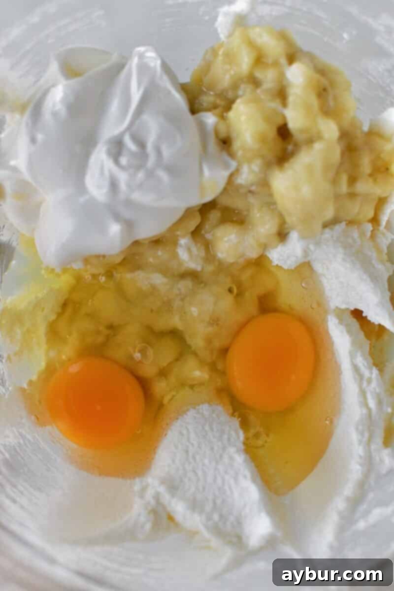 Adding the wet ingredients to the mashed bananas.
