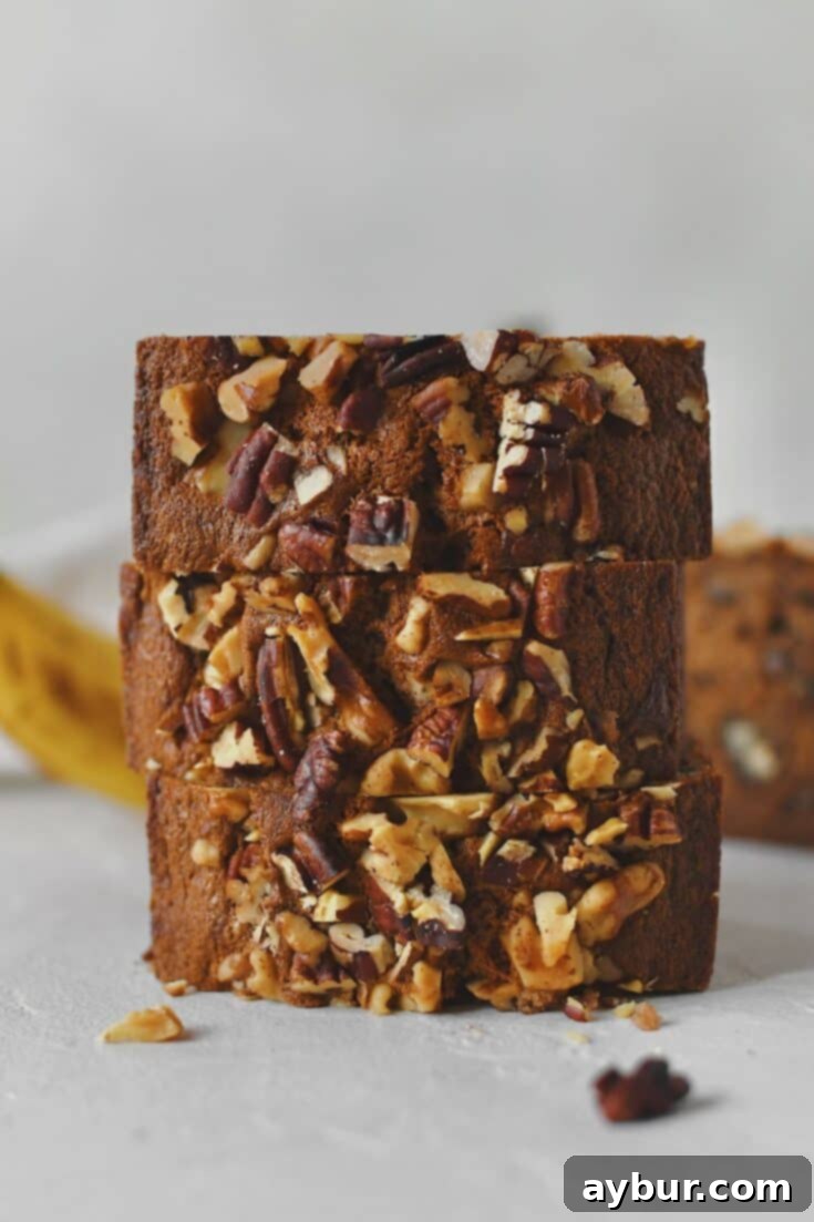 Sliced Starbucks Banana Bread Recipe stacked up with more bananas behind it, ready to eat.