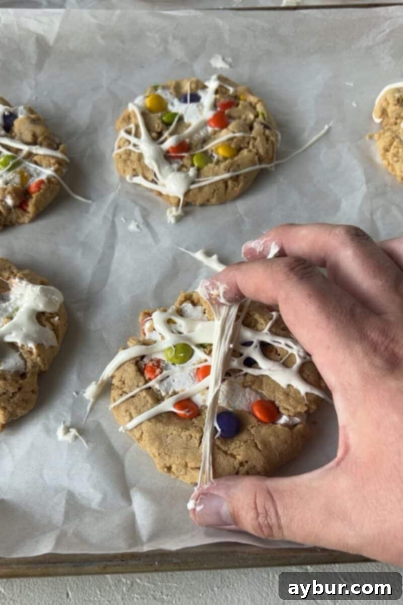 Peanut Butter Kitchen Sink Cookies 11 Hands stretching gooey marshmallow over cookies to create realistic spider web or mummy wrap effects.