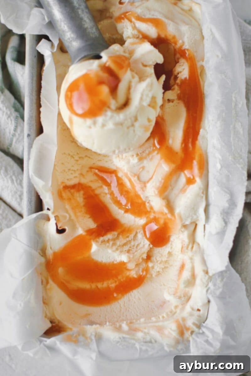 Sweet Peach Dream 11 A scoop of homemade peach ice cream being lifted from a container, showcasing its creamy texture.