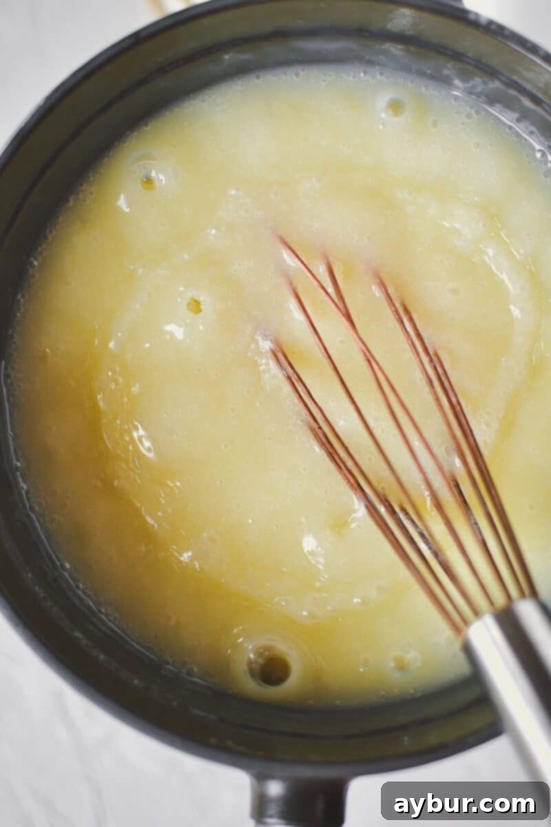 Sweet Peach Dream 5 Whisking the cornstarch slurry into the warm cream mixture to thicken the ice cream base. The mixture becomes smooth and velvety.