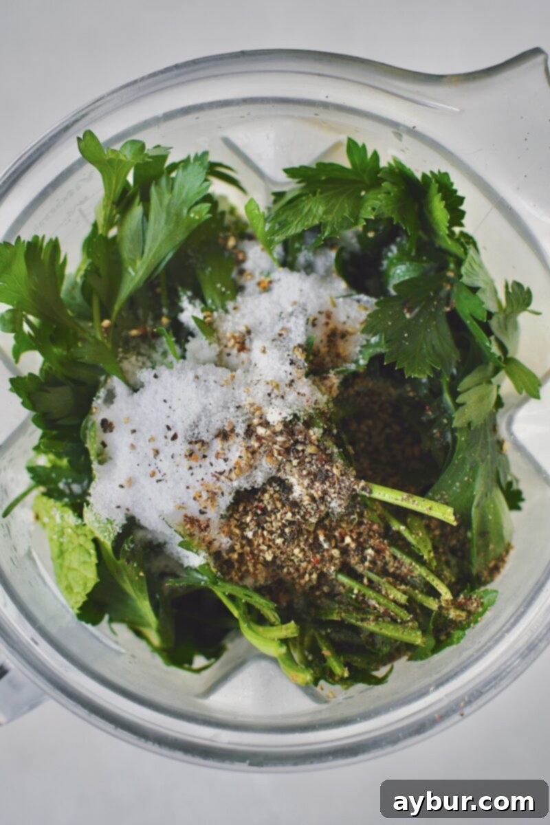 All the fresh ingredients including herbs, garlic, and creamy base, placed inside a blender cup before blending.