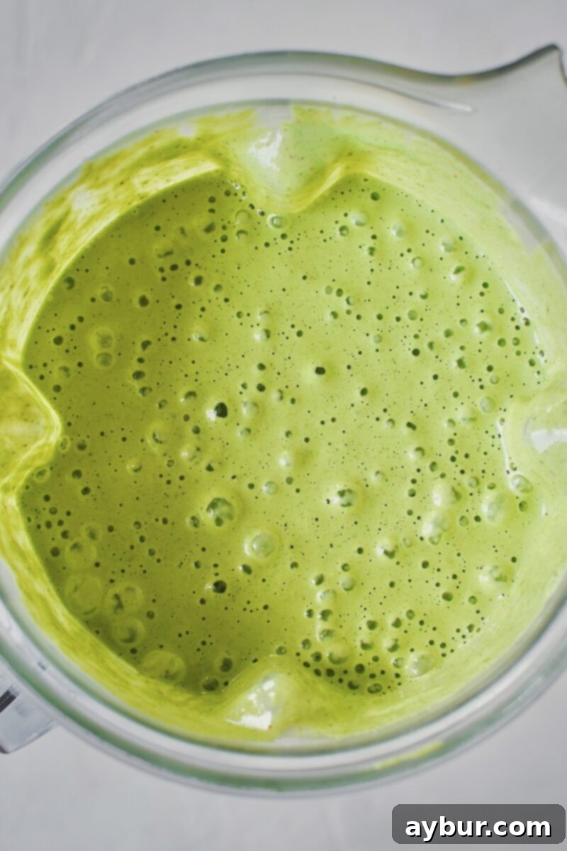 Smooth, blended Green Goddess Dressing in a blender cup, after all ingredients have been processed.