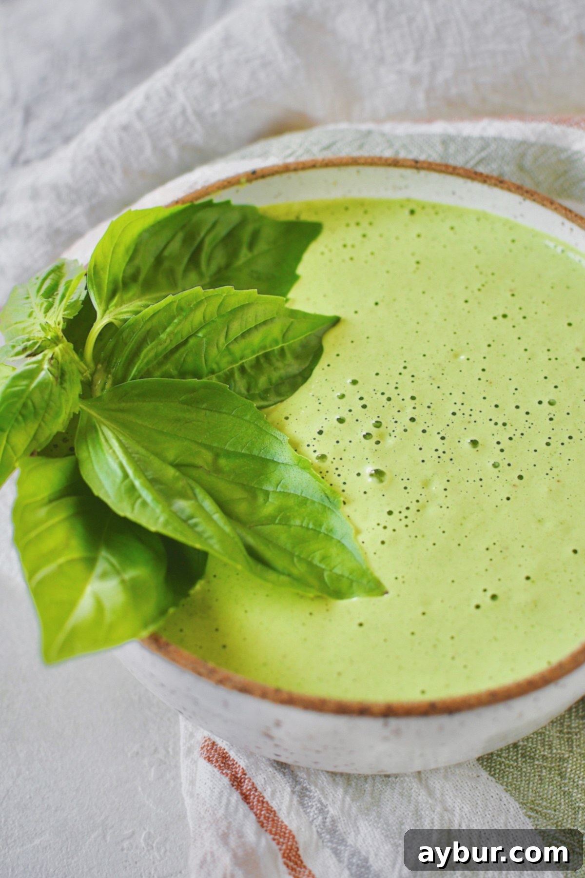 A bowl of freshly prepared Green Goddess Dressing, garnished with basil leaves and ready for serving.
