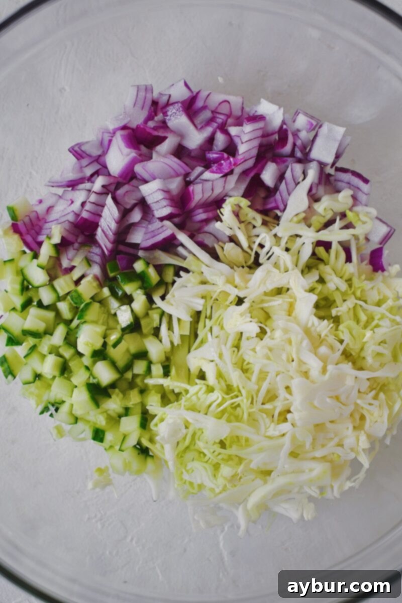 Emerald Goddess Chicken Salad 4 Starting the base of the chicken salad by mixing the cucumber, onion, and shaved cabbage together with the vinegar.