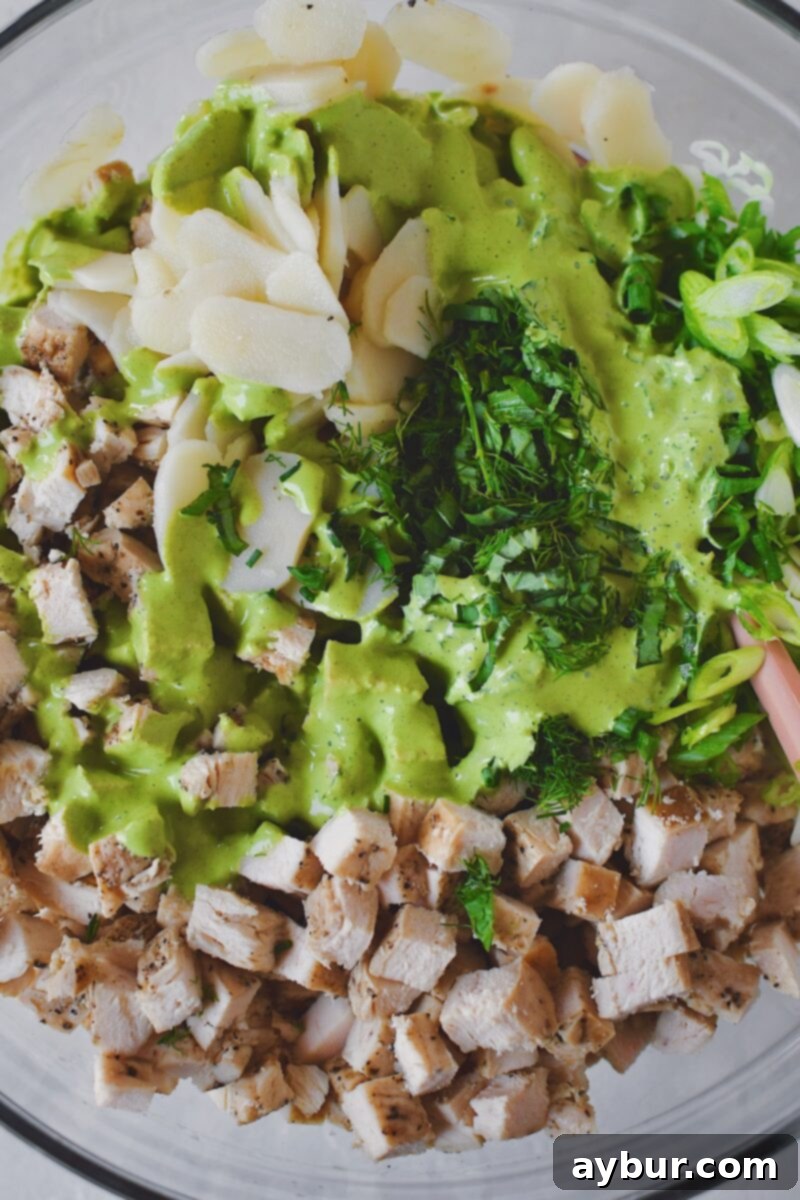 Emerald Goddess Chicken Salad 5 Remaining ingredients and seasonings added to the bowl, before mixing all together to form the chicken salad.