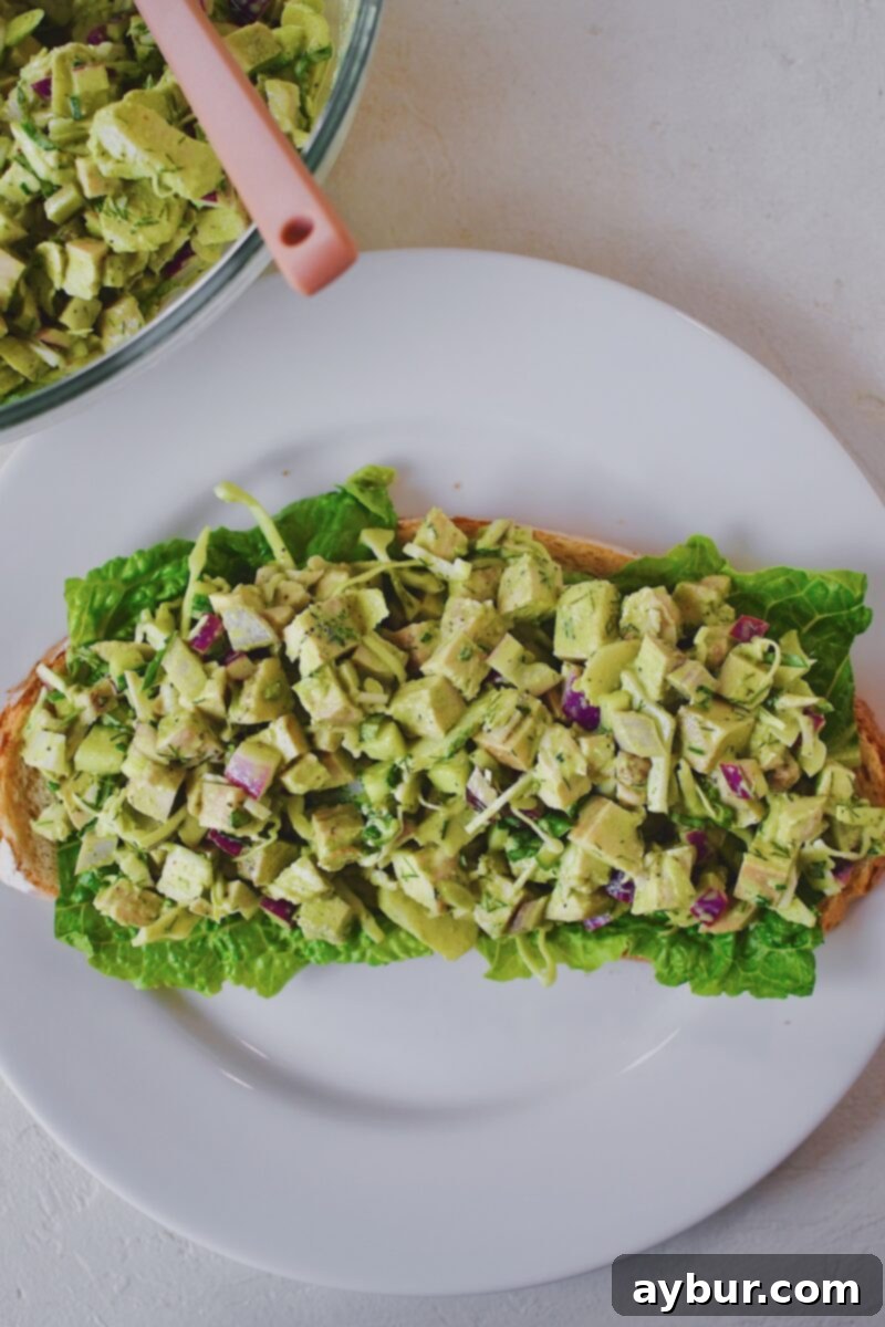 Emerald Goddess Chicken Salad 8 Assembling a sandwich using the chicken salad. Lettuce down on a slice of bread first, with the mixed chicken salad on top.