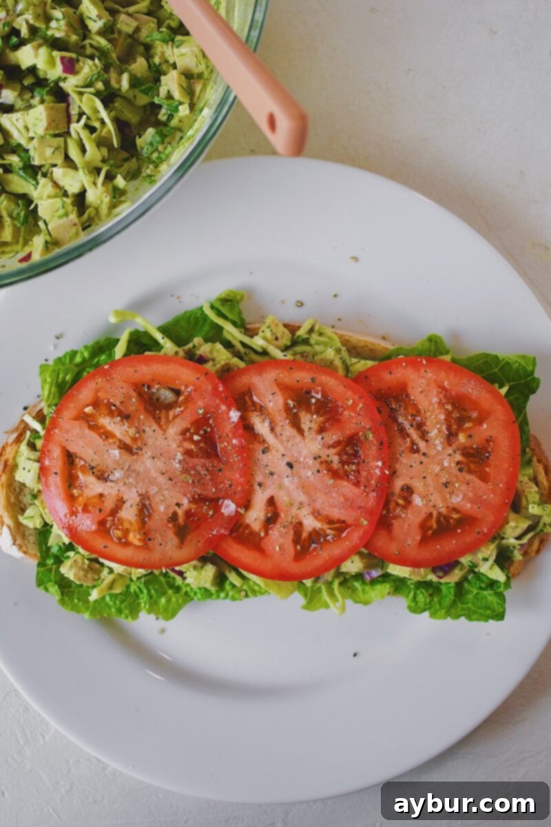 Emerald Goddess Chicken Salad 9 Assembling a sandwich using the chicken salad. Lettuce down on a slice of bread first, with the mixed chicken salad and tomato slices on top.