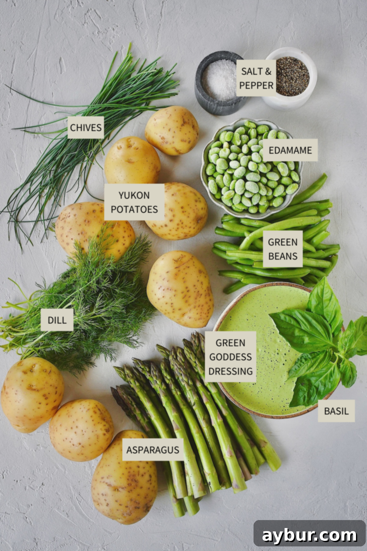 Vibrant Green Goddess Potato Salad 3 A flat lay of fresh ingredients needed to prepare Green Goddess Potato Salad, including potatoes, asparagus, green beans, edamame, and fresh herbs.