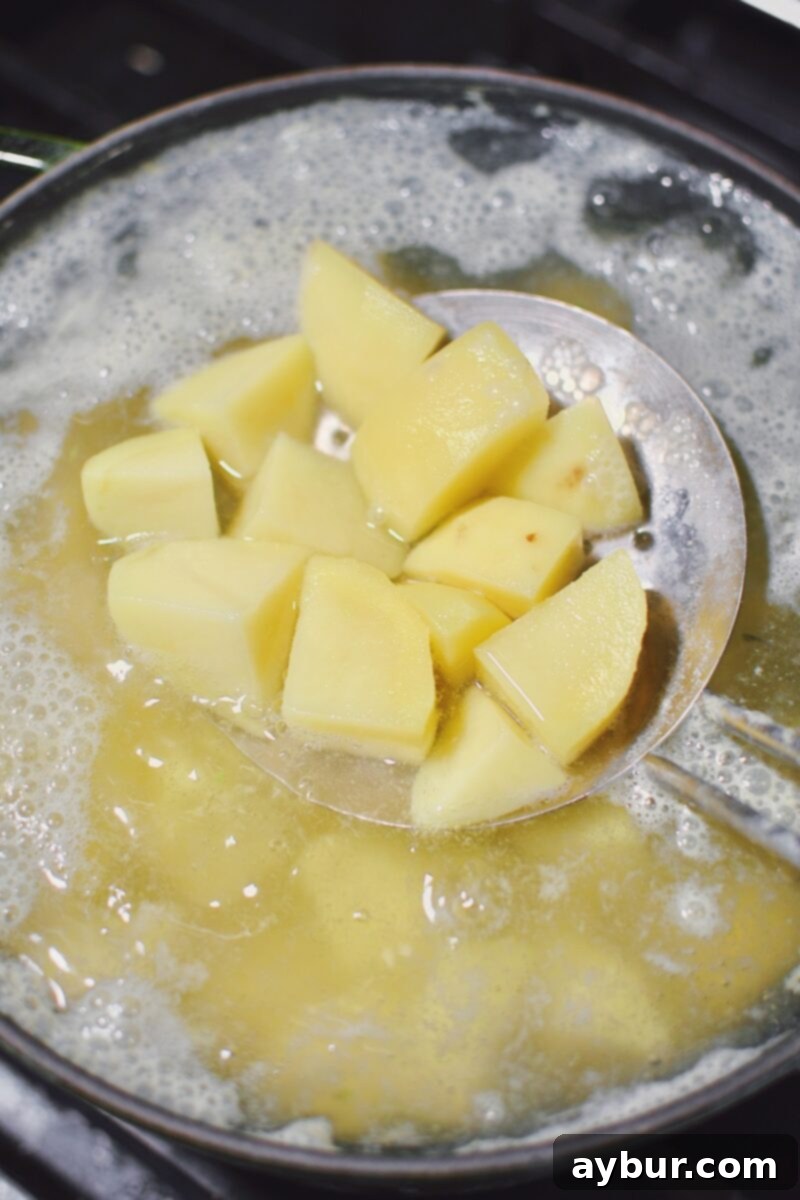 Vibrant Green Goddess Potato Salad 7 Yukon Gold potatoes boiling in a pot of water until tender, ready to be drained.