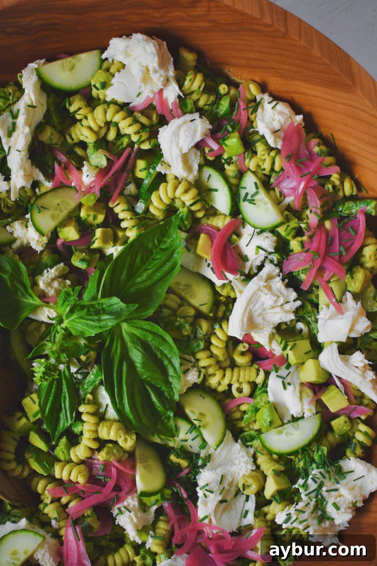 Vibrant Green Goddess Pasta 11 Green Goddess Pasta Salad elegantly presented in a large wooden serving bowl, ready to be enjoyed at a summer gathering.