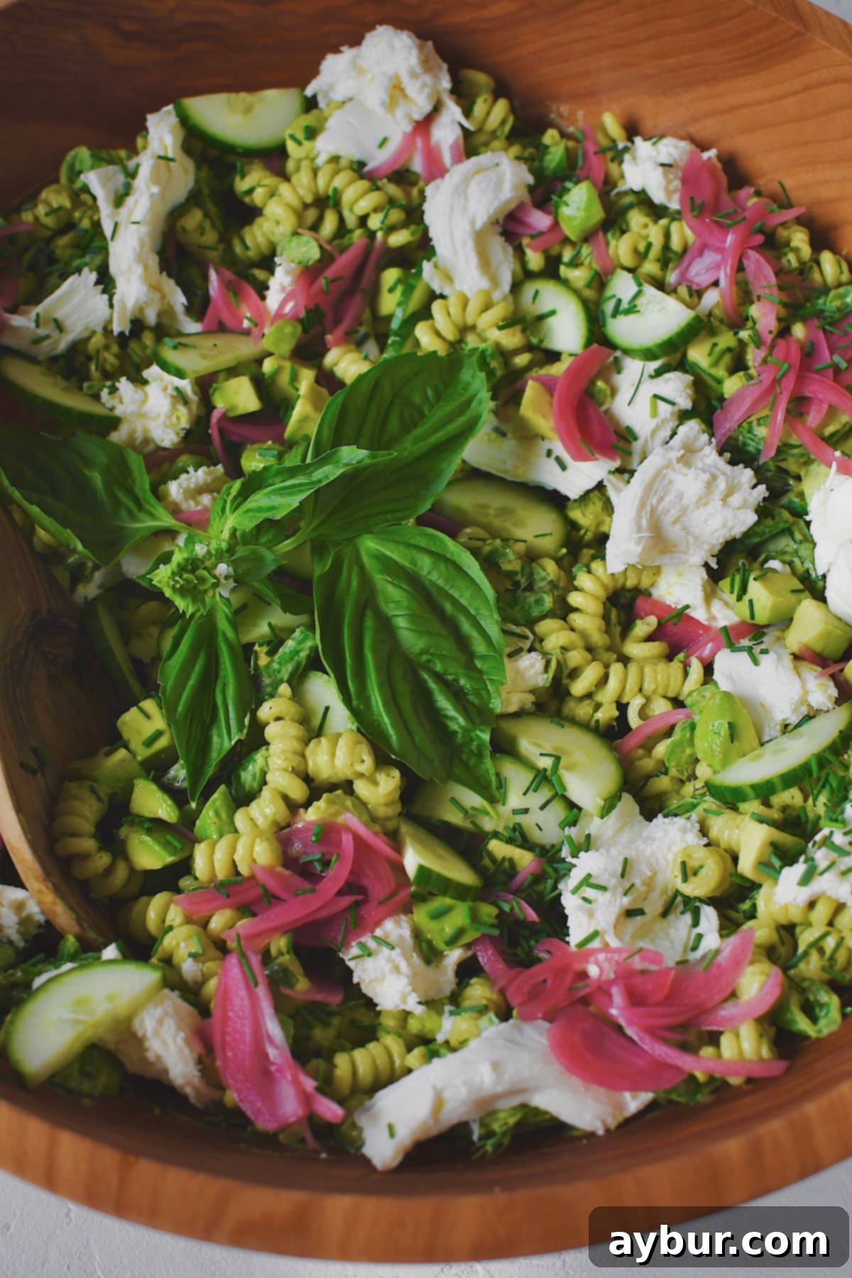 Vibrant Green Goddess Pasta 15 Green Goddess Pasta Salad presented in a large wooden serving bowl with a wooden spoon for serving, showcasing its appealing texture and freshness.