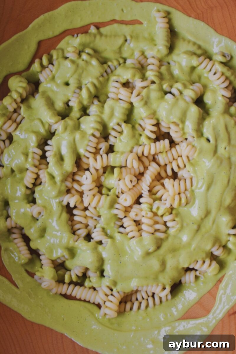 Vibrant Green Goddess Pasta 7 Combining the cooked and cooled pasta in a large bowl with the creamy green goddess dressing, ready for additional ingredients.