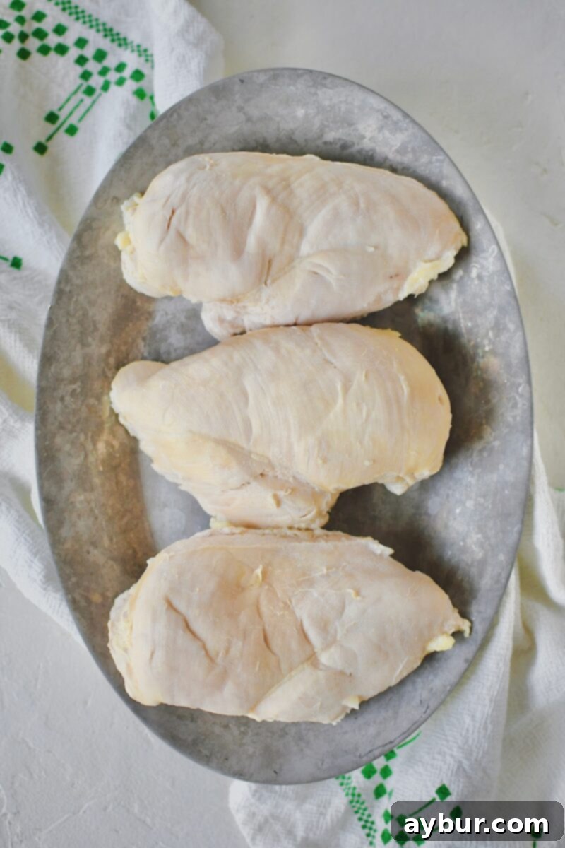 Cooked poached chicken breasts removed from the flavorful liquid, resting.