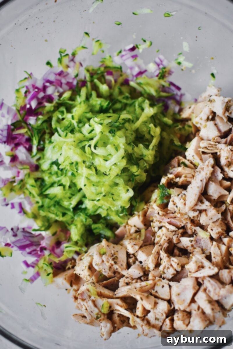Adding finely diced red onion and shredded cucumber to the seasoned chicken mixture for texture and tang.