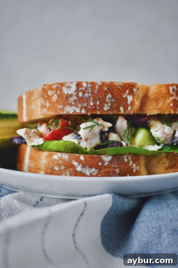 Served on white bread with a side of cucumber stick, a Greek Style Chicken Salad sandwich is ready to be enjoyed.